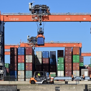 Container werden im Hafen von Kränen transportiert und verladen