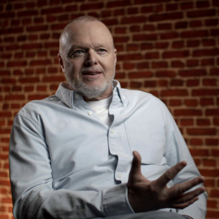 Stefan Raab sitzt in einem Interviewsetting vor einer Ziegelsteinwand.