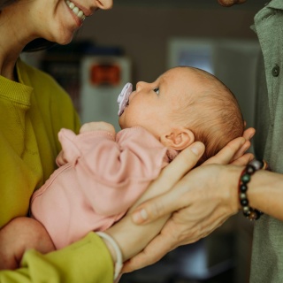 Eltern halten ein Baby mit Schnuller in den Armen