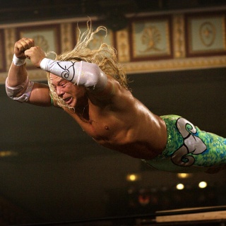 Eine Filmszene aus dem Film "The Wrestler" zeigt den Schauspieler Mickey Rourke mit langen Haaren und bunter Kampfsporthose bekleidet. Er springt mit wehenden Haaren durch die Luft.