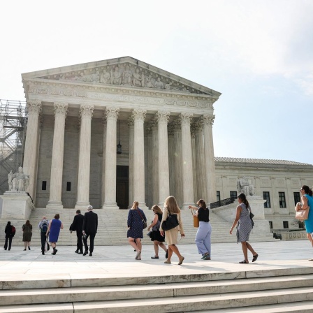 Menschen gehen eine Treppe hoch und in das weiße Gerichtsgebäude des Obersten Gerichtshofs in den USA hinein