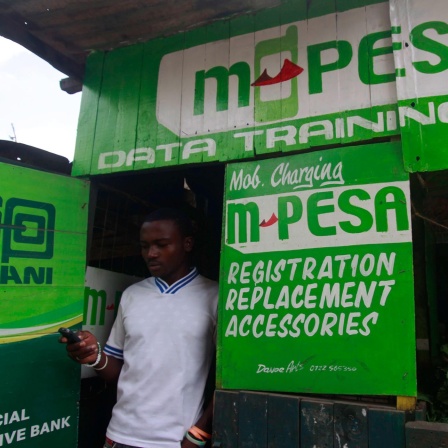 Ein Mann verlässt mit seinem Smartphone in der Hand einen M-Pesa-Service-Laden in Nairobi. 