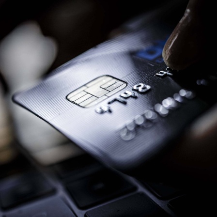  Eine Kreditkarte vom Typ VISA Card wird neben einer Computertatstatur gehalten. 