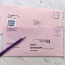 Zwei Briefe zur Sozialwahl 2023 liegen auf einem Marmortisch gemeinsam mit einem lila Kuli. 