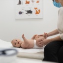 Ein Baby liegt auf einer Liege beim Kinderarzt. 