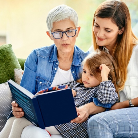Oma, Mutter und Tochter lesen gemeinsam ein Buch