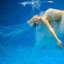 Ein Braut schwebt mit ihrem Kleid unter Wasser.