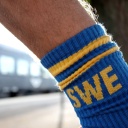 Bahnurlaub in Schweden. Socken in schwedischen Farben und mimit SWE Schriftzug vor einem Wagen der schwedischen Eisenbahngesellschaft SJ in Emmaboda.