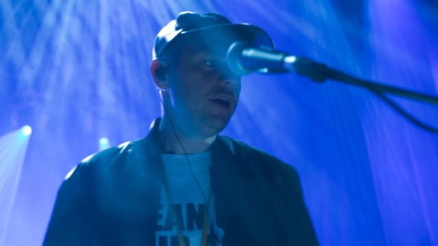 Ein Mann mit Basecap singt in ein Mikrofon.