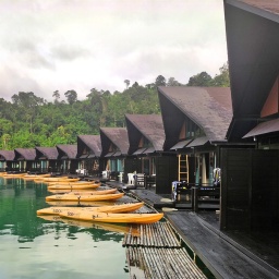 Boote liegen vor schwimmenden Bungalows auf dem jadegrünen Chian-Lan See in Thailand