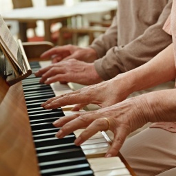 Ein Seniorenpaar spielt gemeinsam am Klavier.