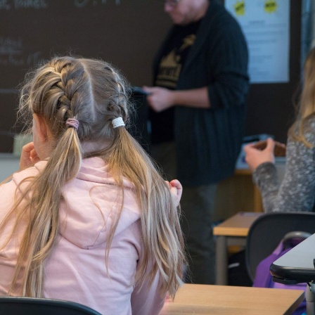 Ein Mädchen sitzt in seinem Klassenraum und verfolgt den Unterricht. 