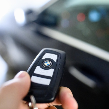 Ein Mann hält den Schlüssel eines BMW in der Hand.
