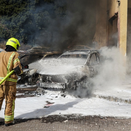 Feuerwehrman in Israel versucht nach einem Angriff der Hamas das Feuer auf Autos zu löschen