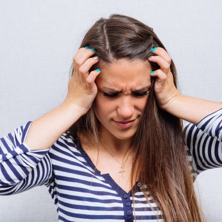 Eine Frau hält sich mit schmerzverzerrtem Gesicht die Ohren zu: Migräne ist eine ernste Erkrankung. Man muss sie intensiv behandeln, um Komplikationen wie Tinnitus möglichst zu vermeiden.