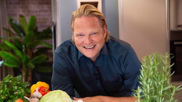 Björn Freitag in der Küche mit einem Korb Gemüse.