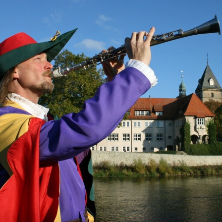 Der Rattenfänger von Hameln posiert mit seiner Flöte an der Weser.