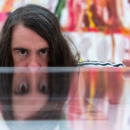 Jonathan Meese, Maler und Aktionskünstler, spiegelt sich in dem Ausstellungsraum der Ausstellung "Die Irrfahrten des Meese" in einem Schaukasten.