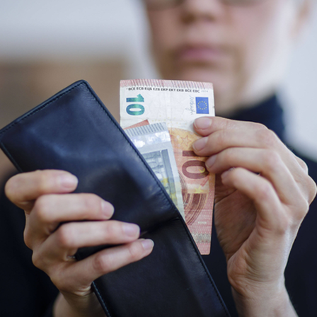 Frau zieht Euro-Scheine aus einem Portemonnaie