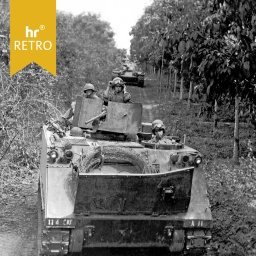 Vietnamkrieg: Truppentransporter mit Soldaten in bewaldeter Schneise, weitere Fahrzeuge folgen.