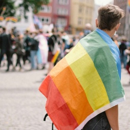Symbolbild queere Gesellschaft: Ein Mann trägt eine Regenbogenfahne über der Schulter