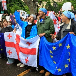 Demonstrierende in Georgien mit der georgischen und der EU-Flagge.