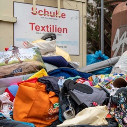 Berge von Altkleidern vor Sammelcontainern