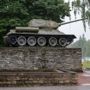 Ein historischer Sowjetpanzer steht im estnischen Narva auf einem Steinsockel, im Hintergrund sind Bäume zu sehen.