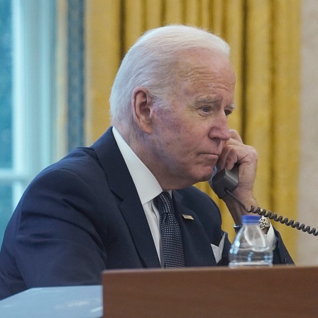 Auf diesem Bild, das durch ein Fenster aufgenommen wurde, telefoniert der Präsident der USA, Joe Biden, im Oval Office des Weißen Hauses.
