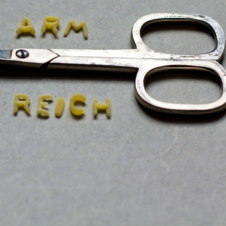Über einer Schere steht "arm", darunter "reich".