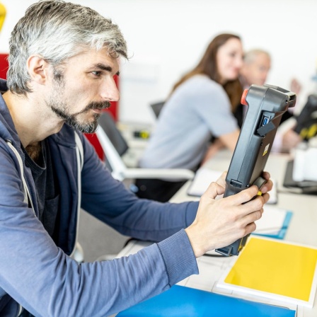 Industriemechaniker arbeitet an einem Roboterarm mit digitaler Steuerung