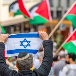 Ein Pro-Israel-Demonstrant hält einer Free-Palestine-Demonstration die israelische Flagge entgegen