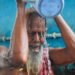 Ein Mann in Indien schüttet sich Wasser über den Kopf