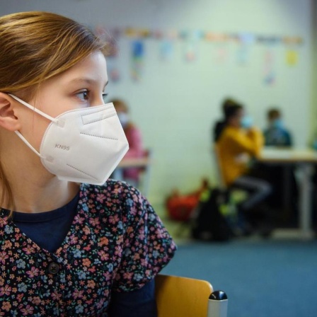 Eine Schülerin einer 4. Klasse sitzt im Unterricht an der Grundschule Russee in Kiel mit einer FFP-2-Maske an ihrem Platz. 