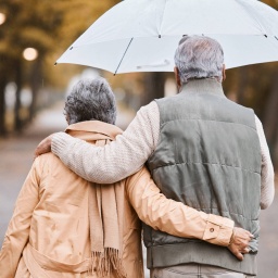 Zwei Senioren spazieren im Regen