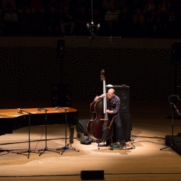 Drei Männer mit Musikinstrumenten musizieren auf einer Bühne