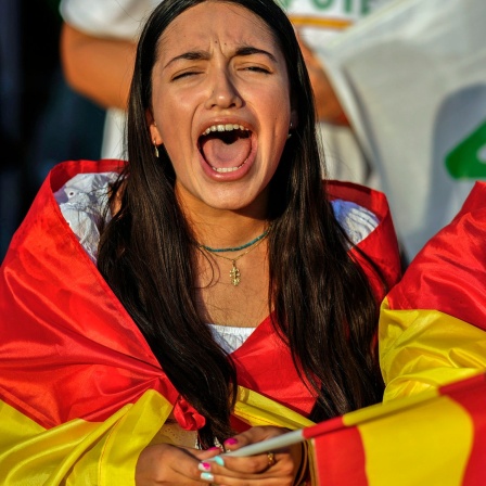 In eine spanische Flagge gehüllte Anhänger der rechtsextremen Partei VOX jubeln während der Abschlusskundgebung auf dem Colon-Platz in Madrid (Spanien).