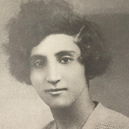 Abgebildet ist Louisa Aslanian. Ein Schwarz-Weiß-Bild einer jungen Frau mit kurzen dunklen Haaren, die verträumt in die Kamera blickt. 