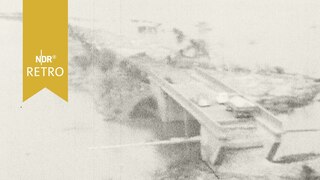 Brückenrest, auf dem Autos stehen, die Straße beiderseits ist weggespült (1962)