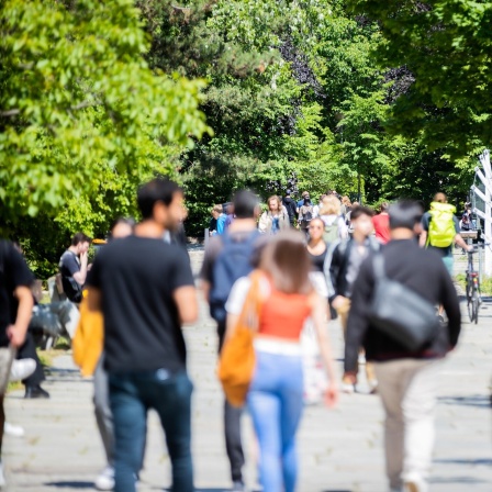 Menschen gehen beim Studierendenwerk Berlin über den Uni-Campus.