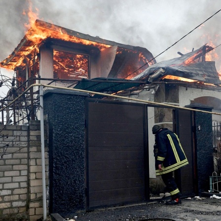 Ein Feuerwehrmann steht vor einem brennenden Haus im ukrainischen Cherson, das nach ukrainischen Angaben bei russischem Beschuss am orthodoxen Weihnachtsabend getroffen wurde. 