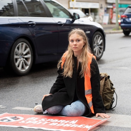 Klimaschutz-Demonstrantin Aimée van Baalen sitzt auf einer Fahrbahn. 