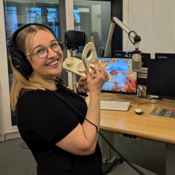 Geräuschemacherin Franziska Treutler steht mit einem Eierschneider in einem Radiostudio.