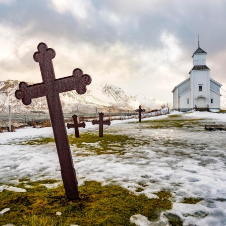 Gimsøy Kirche mit Friedhof, hinten schneebedeckte Berge, Winter, Gimsøya, Lofoten, Norwegen, Europa