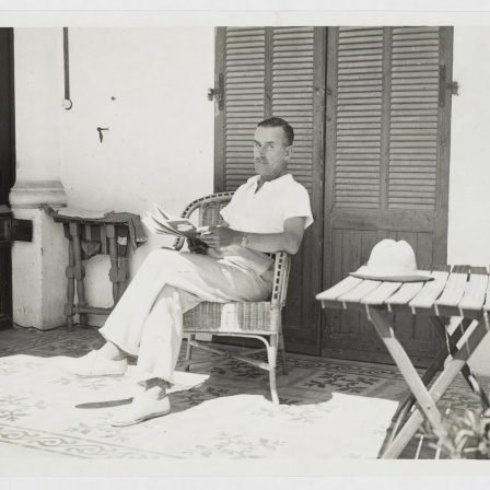 Thomas Mann sitzend mit einem Buch in der Hand auf der Veranda