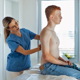 Eine Hautärztin schaut sich den Rücken eines Patienten an.