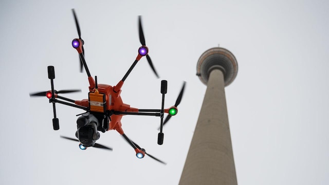 Eine Mess-Drohne steigt am Schaft des  Berliner Fernsehturms empor.
