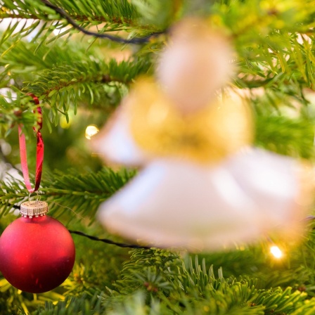 Geschmückter Weihnachtsbaum mit Stern, roter Kugel und Engelsfigur.