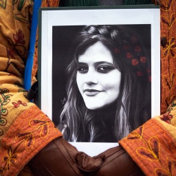 Ein Demonstrant behält ein Bild von Mahsa Amini in beiden Händen. 