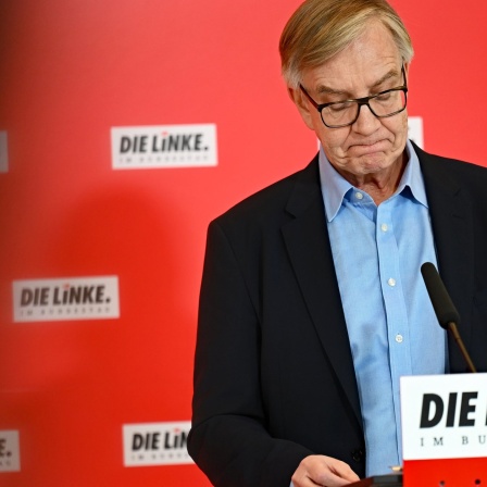 Dietmar Bartsch steht mit gesenktem Haupt an einem Redepult der Partei "Die Linke".